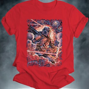 May include: Red t-shirt featuring a stylized illustration of The Mandalorian in a starry night setting. The artwork depicts the character in detailed armor, surrounded by swirling clouds and laser beams. The design is reminiscent of a famous painting.