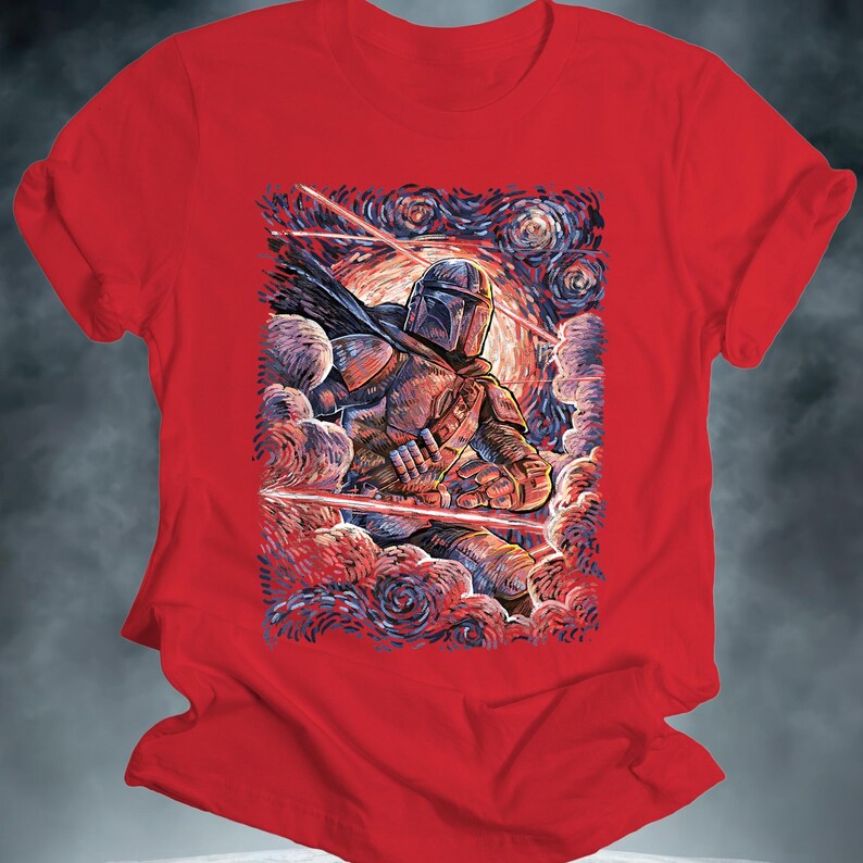 May include: Red t-shirt featuring a stylized illustration of The Mandalorian in a starry night setting. The artwork depicts the character in detailed armor, surrounded by swirling clouds and laser beams. The design is reminiscent of a famous painting.
