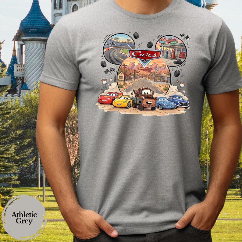 Pode incluir: Uma t-shirt cinzenta de manga curta com uma impress&atilde;o gr&aacute;fica das personagens do filme Cars da Disney Pixar. O design inclui o Fa&iacute;sca McQueen, o Mate e outros ve&iacute;culos num cen&aacute;rio de deserto com o log&oacute;tipo Cars e uma pista.