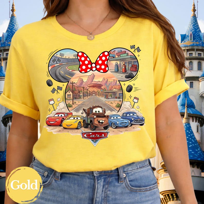 Pode incluir: Uma t-shirt amarela brilhante com uma impress&atilde;o gr&aacute;fica das personagens do filme Carros, incluindo Rel&acirc;mpago McQueen e Mate, num cen&aacute;rio de deserto. Por cima dos carros, h&aacute; um la&ccedil;o vermelho com bolinhas brancas e uma pista.