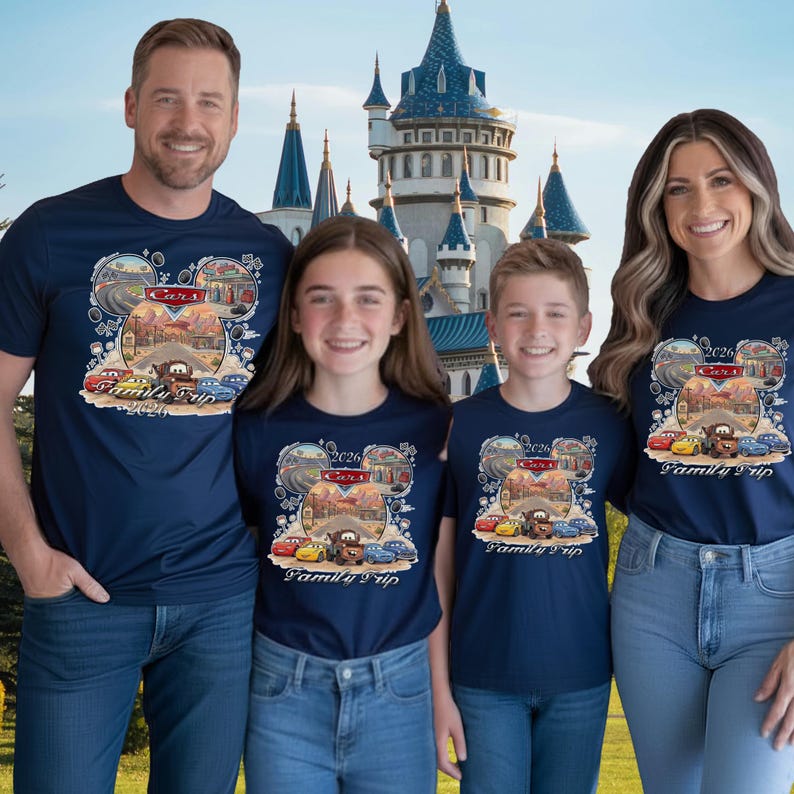 Puede incluir: Cuatro personas con camisetas azul marino con un dise&ntilde;o tem&aacute;tico de Cars. El dise&ntilde;o incluye el texto "Cars", "2026" y "Family Trip". El fondo presenta un castillo y un cielo azul.
