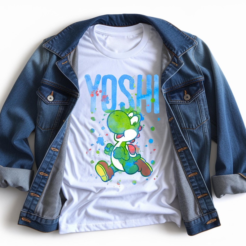 May include: A white t-shirt with a graphic of Yoshi, a green dinosaur character, and the word "YOSHI" in blue. The shirt is styled with a blue denim jacket. The design includes colourful paint splatters.