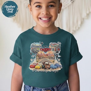 Puede incluir: Una camiseta verde azulado con un gr&aacute;fico de los personajes de la pel&iacute;cula Cars en forma de cabeza de Mickey Mouse. El dise&ntilde;o incluye el texto "2026 Cars Family Trip" e im&aacute;genes de pistas de carreras y una gasolinera.