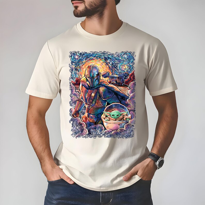May include: A cream t-shirt with a colourful graphic depicting The Mandalorian and Grogu in a starry night style. The artwork shows the Mandalorian in armour and Grogu in his pod, with a vibrant, artistic sky.