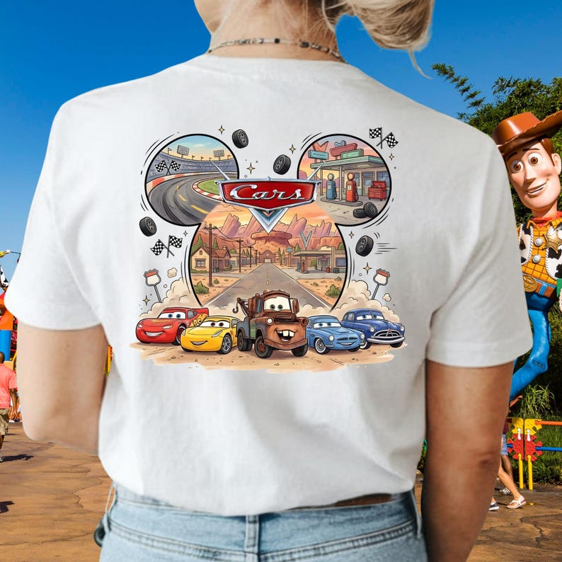 Pu&ograve; includere: Una t-shirt bianca con una stampa grafica dei personaggi del film Cars della Disney Pixar, tra cui Saetta McQueen, Cricchetto e altri. Il design include una scena stradale centrale, un circuito, una stazione di servizio e il logo Cars in rosso.