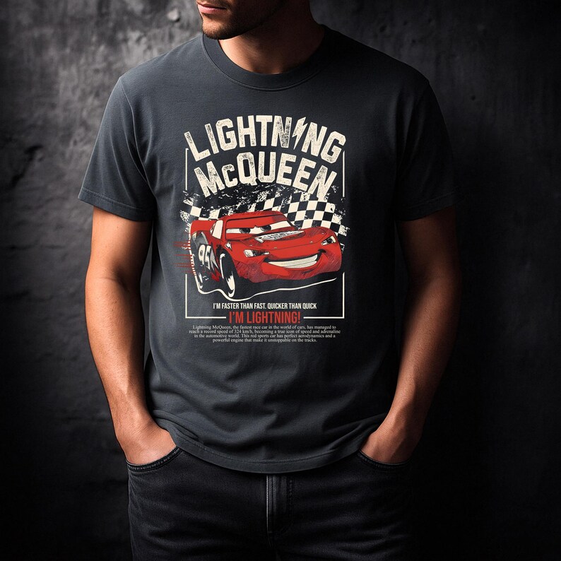 May include: Dark gray t-shirt featuring a graphic of Lightning McQueen from the Cars movie. The design includes the text "LIGHTNING McQUEEN" above a red race car with the number 95. Below the car is the phrase "I'M LIGHTNING!"