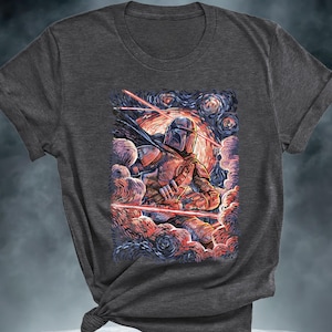 May include: Dark gray t-shirt featuring a stylized illustration of a Mandalorian warrior against a starry night sky. The artwork includes red laser beams and a vibrant color palette, creating a dynamic and artistic design.