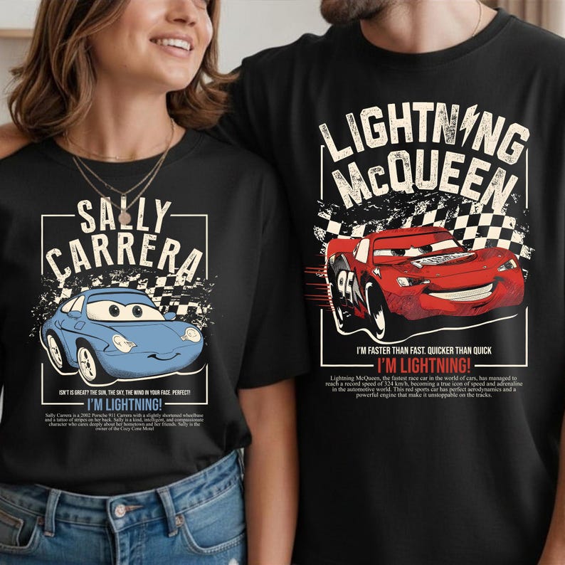 May include: Black t-shirts featuring characters from the movie Cars. One shirt displays a blue car with "SALLY CARRERA" text. The other shirt shows a red car with "LIGHTNING McQUEEN" text and the phrase "I'M LIGHTNING!"