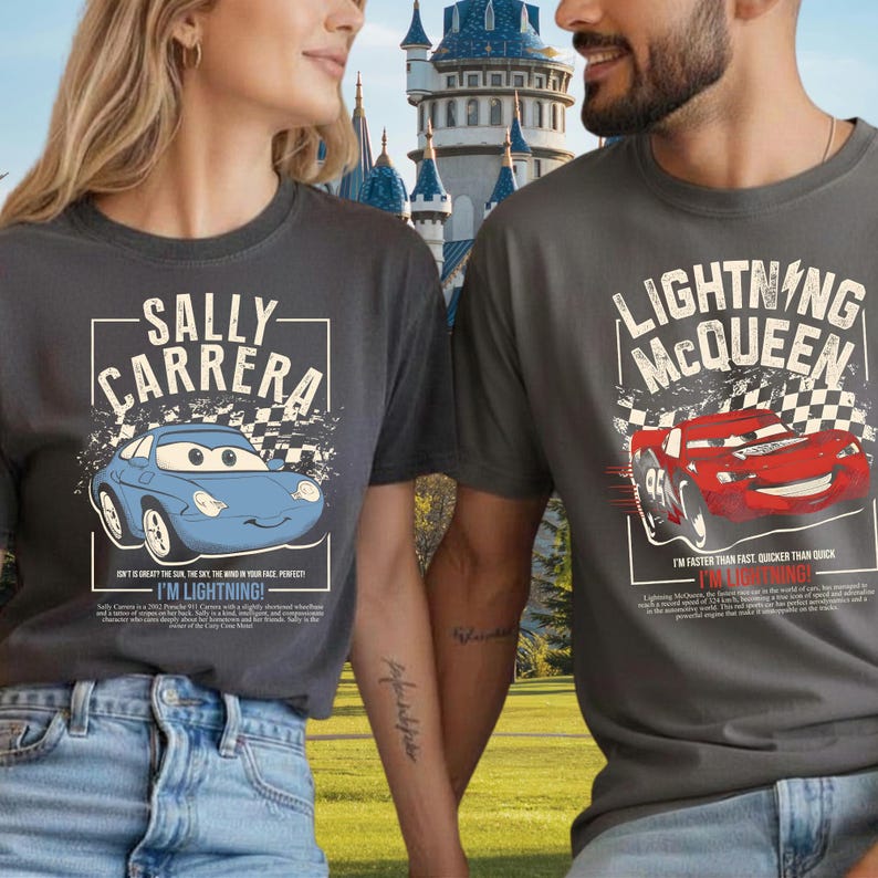 May include: Two charcoal gray t-shirts featuring characters from the movie Cars. One shirt displays "SALLY CARRERA" with a blue car graphic and the text "I'M LIGHTNING!". The other shirt shows "LIGHTNING MCQUEEN" with a red car graphic and the text "I'M LIGHTNING!"