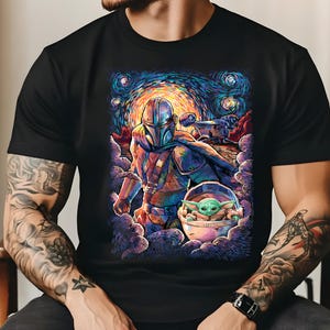 May include: Black t-shirt with a colourful illustration of The Mandalorian and Grogu, set against a starry night sky. The artwork has a painterly style with swirling clouds and vibrant hues of blue, orange, and green. The design includes a spaceship.