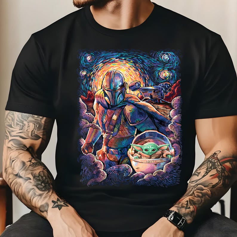 May include: Black t-shirt with a colourful illustration of The Mandalorian and Grogu, set against a starry night sky. The artwork has a painterly style with swirling clouds and vibrant hues of blue, orange, and green. The design includes a spaceship.