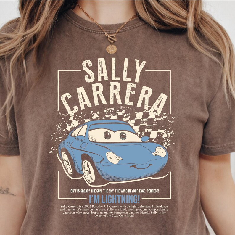 May include: Brown t-shirt featuring a blue cartoon car with the text "SALLY CARRERA" above it. The text "I'M LIGHTNING!" is below the car. The shirt has a vintage, distressed look.