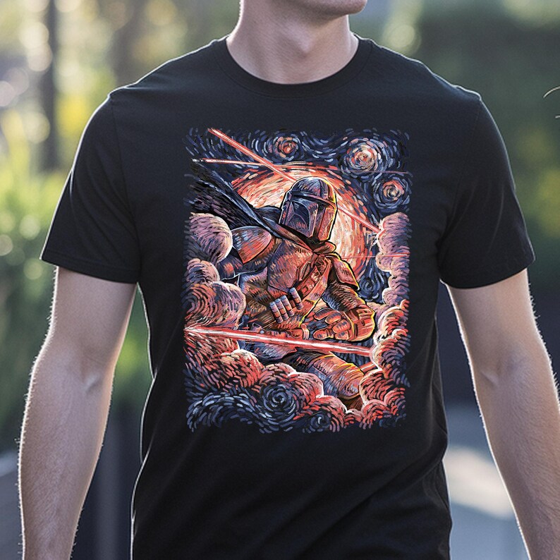 May include: Black t-shirt featuring a stylized illustration of The Mandalorian in a dynamic pose, set against a swirling, colorful background reminiscent of Van Gogh's style. The artwork includes red laser beams and a starry sky.