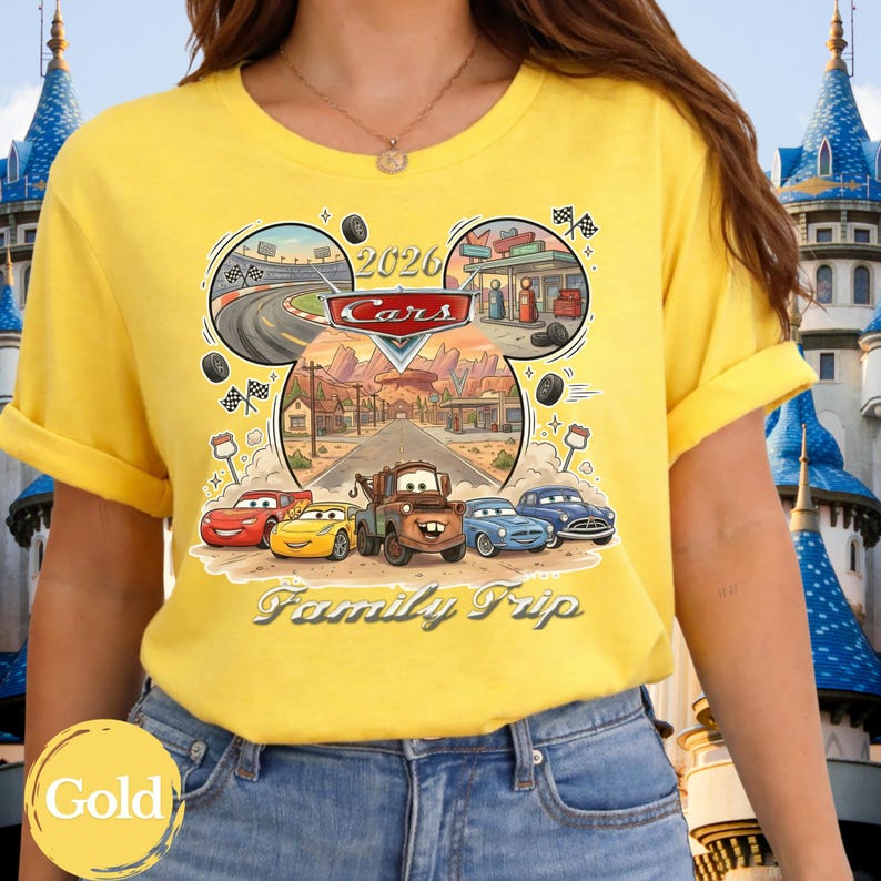 Puede incluir: Camiseta amarilla con un dise&ntilde;o tem&aacute;tico de Cars, con el texto "2026 Cars Family Trip". El dise&ntilde;o incluye coches de dibujos animados, una carretera y una gasolinera. La camiseta tiene mangas cortas y cuello redondo.