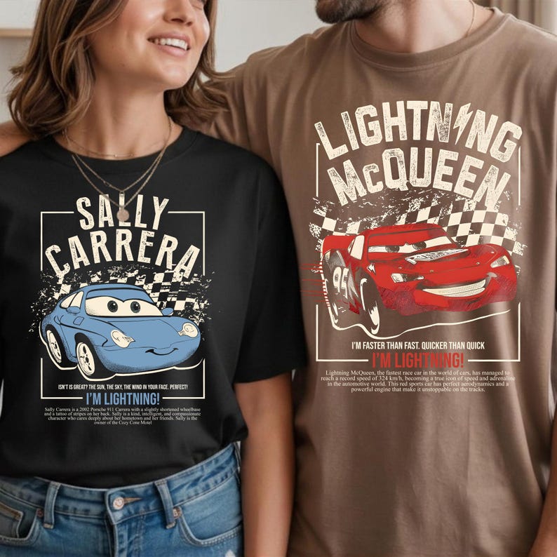 May include: Two t-shirts, one black and one brown, featuring cartoon car graphics. The black shirt displays a blue car with "SALLY CARRERA" text. The brown shirt shows a red car with "LIGHTNING McQUEEN" text. Both shirts have additional text.
