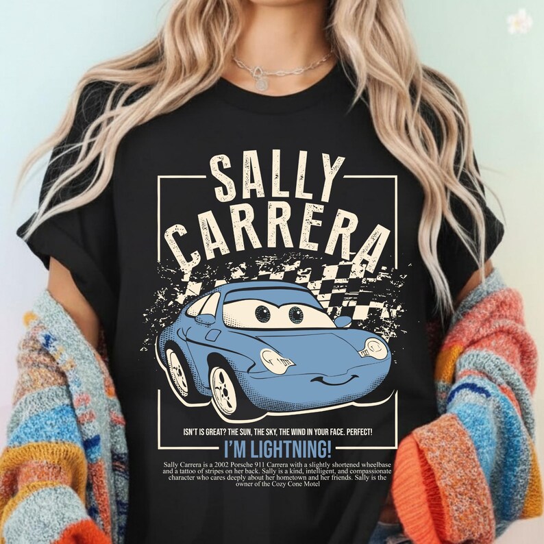 May include: Black t-shirt featuring a cartoon image of Sally Carrera, a blue Porsche 911, with the text "SALLY CARRERA" above the car. The shirt also includes the phrase "I'M LIGHTNING!"