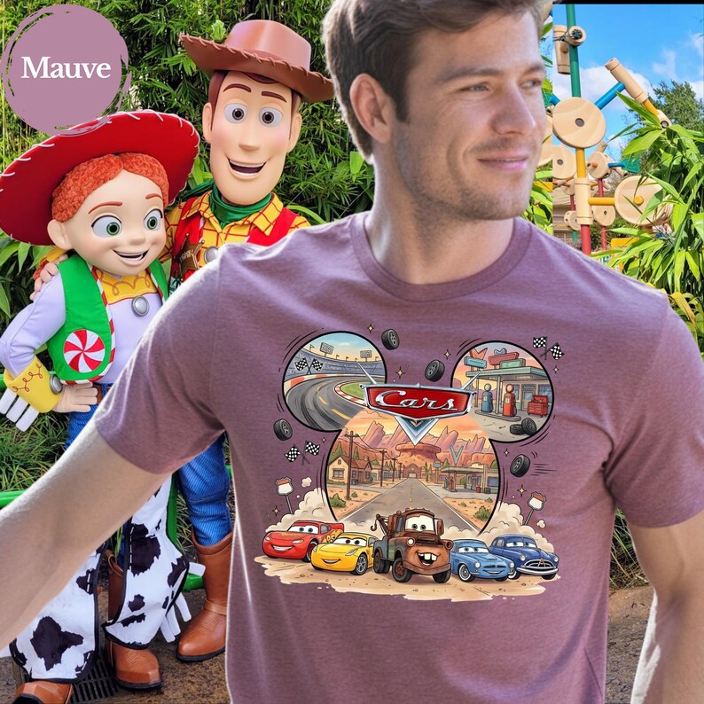 Pode incluir: Uma t-shirt de manga curta cor de malva com um gr&aacute;fico das personagens Disney Pixar Cars, incluindo Rel&acirc;mpago McQueen, Mate e outros. O design inclui uma moldura em forma de orelhas do Mickey com cenas de uma pista e Radiator Springs.