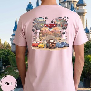 Pu&ograve; includere: Una t-shirt rosa chiaro con una grafica sul retro che mostra il logo Disney Cars e personaggi come Saetta McQueen, Cricchetto e altri veicoli. Il design &egrave; incorniciato a forma di orecchie di Topolino e mostra una scena di strada nel deserto.