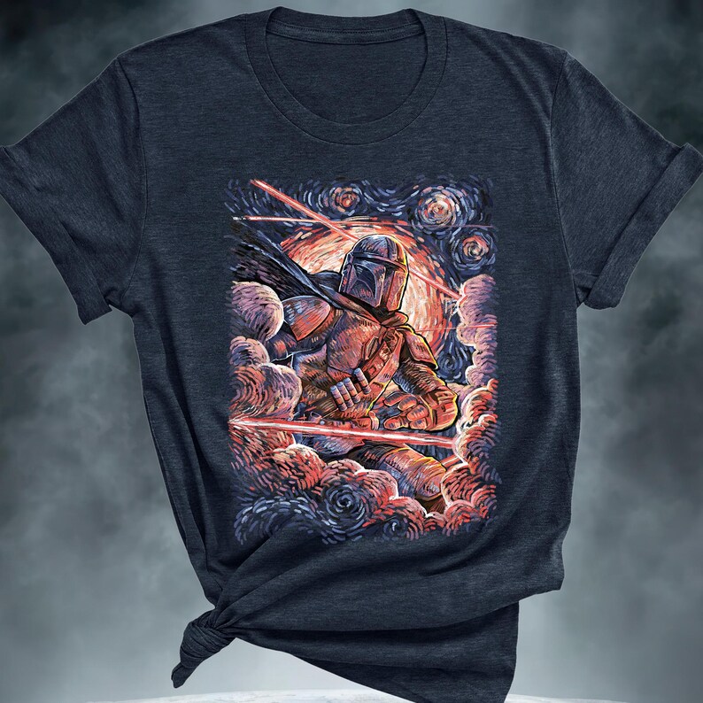May include: Dark navy blue t-shirt featuring a colorful illustration of a character in armor, set against a swirling, starry background with red laser beams. The artwork evokes a blend of science fiction and classic art styles.