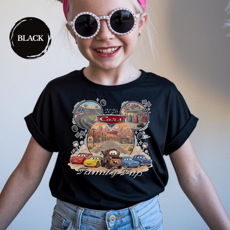 Puede incluir: Camiseta negra con un gr&aacute;fico colorido de los personajes de Cars y el texto "2026 Cars Family Trip". El dise&ntilde;o incluye im&aacute;genes de pistas de carreras, gasolineras y paisajes des&eacute;rticos. La camiseta es de cuello redondo.