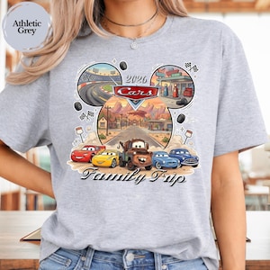 Puede incluir: Camiseta gris deportivo con un gr&aacute;fico colorido de Cars. El dise&ntilde;o presenta personajes de Cars, una carretera des&eacute;rtica y el texto "2026 Cars Family Trip". La camiseta es de material suave.
