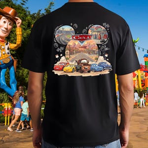 Pu&ograve; includere: Una t-shirt nera con una stampa grafica del logo Disney Pixar Cars e personaggi come Saetta McQueen e Cricchetto. Il design a forma di orecchie di Topolino raffigura una strada nel deserto con elementi da corsa e bandiere a scacchi.