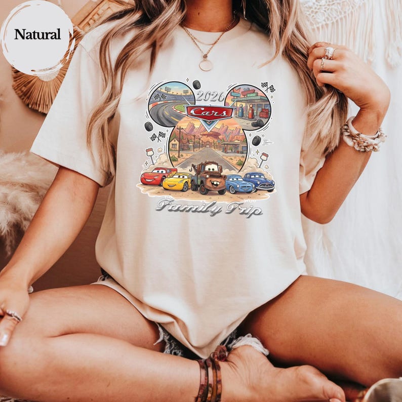 Puede incluir: Camiseta beige con un gr&aacute;fico colorido de los personajes de la pel&iacute;cula Cars. El dise&ntilde;o incluye el texto "2020 Cars" y "Family Trip". La camiseta tiene mangas cortas y cuello redondo.