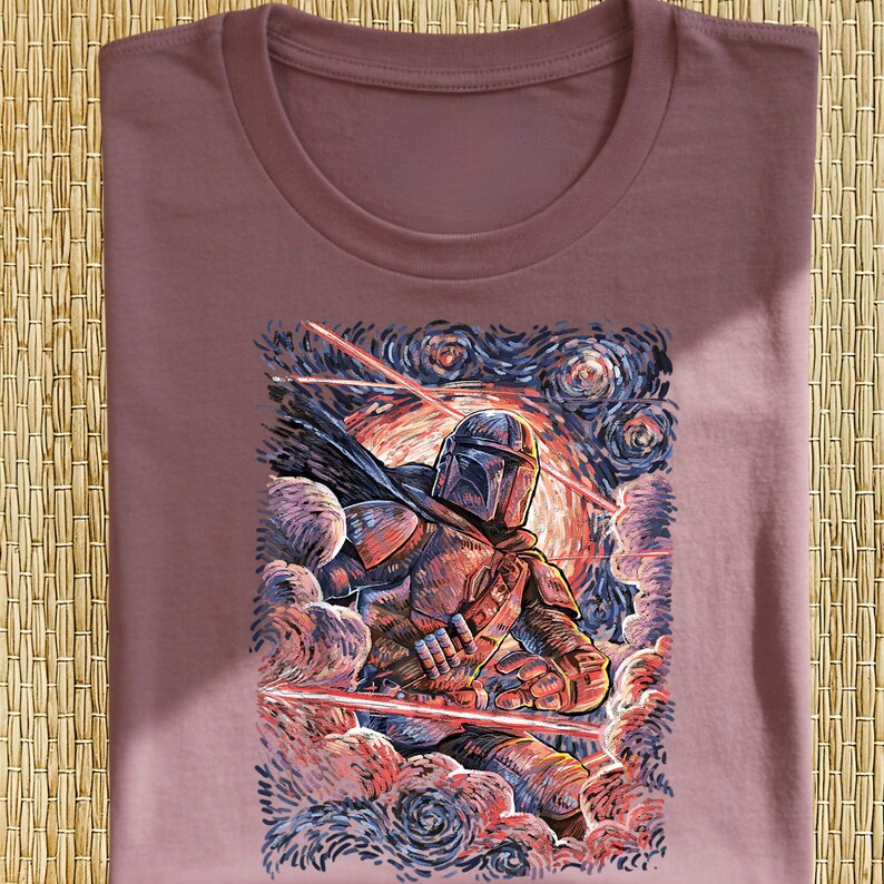 May include: Mauve t-shirt featuring a stylized illustration of a character in armor, with a helmet and cape, amidst swirling clouds and laser beams. The artwork has a painterly style with a starry night sky background.