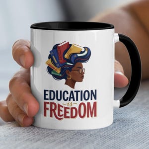 White mug with black rim features woman with books in hair and "EDUCATION IS FREEDOM" text.
