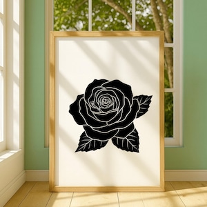 Pu&ograve; includere: Una stampa artistica incorniciata con un'illustrazione di rosa in bianco e nero. La rosa &egrave; raffigurata in uno stile grafico con petali e foglie dettagliati. L'opera d'arte &egrave; presentata in una cornice di legno chiaro.