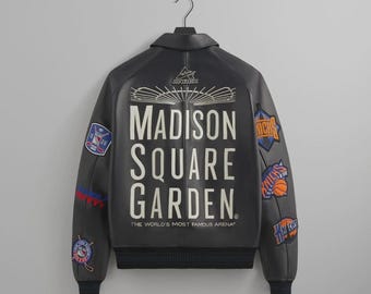 Könnte beinhalten: Schwarze Lederjacke mit dem weißen Schriftzug "MADISON SQUARE GARDEN". Die Jacke hat mehrere Aufnäher mit Teamlogos und den Text "THE WORLD'S MOST FAMOUS ARENA" am unteren Rand.