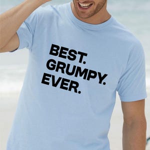 Op de afbeelding: Lichtblauw T-shirt met de zwarte tekst "BEST. GRUMPY. EVER.". Het shirt heeft korte mouwen en een ronde hals. De tekst is vetgedrukt en zonder schreef.