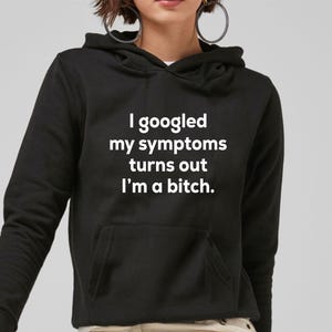 May include: Black hooded sweatshirt with the text "I googled my symptoms turns out I'm a bitch" in white. The sweatshirt has a front pocket and a drawstring hood.