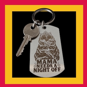 May include: A silver-toned metal keyring featuring a rectangular tag with rounded corners and a split ring. The tag is engraved with a graphic of a fluffy cat wearing sunglasses and a crown, holding a cocktail, with the text MAMA NEEDS A NIGHT OFF.