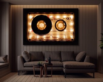 May include: A large, illuminated cassette tape art piece hangs above a gray sectional sofa. The cassette is black and clear with warm, yellow lighting. The room has a modern, minimalist design with a neutral color palette.
