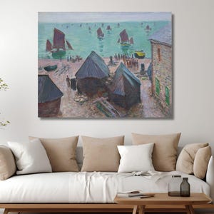 May include: A framed canvas print of a coastal scene. The artwork depicts a harbour with boats, buildings, and figures. The colour palette includes blues, greens, and browns, creating a serene and picturesque view.