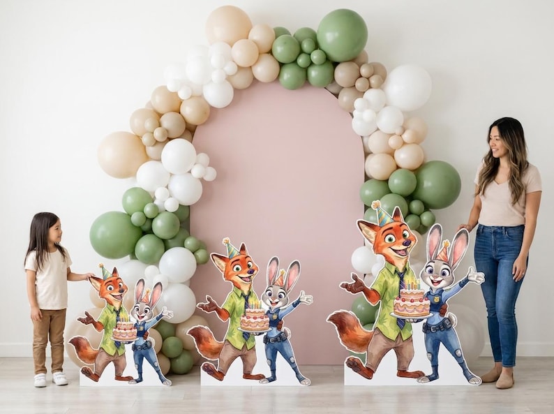 May include: Party decorations featuring Zootopia characters, including Nick Wilde and Judy Hopps, holding a cake. A balloon arch in neutral tones frames a pink backdrop. A young girl and a woman stand nearby.