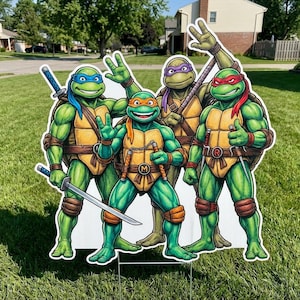 May include: A large, white yard decoration featuring the Teenage Mutant Ninja Turtles. The four turtles are depicted in their signature colors: blue, red, purple, and orange. Each turtle is holding a weapon or making a hand gesture.