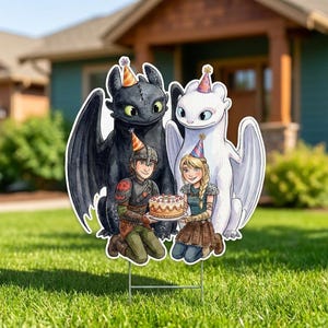 May include: A colorful yard sign featuring a black dragon and a white dragon, each wearing a party hat, with two people holding a birthday cake. The sign is set on a green lawn in front of a house.