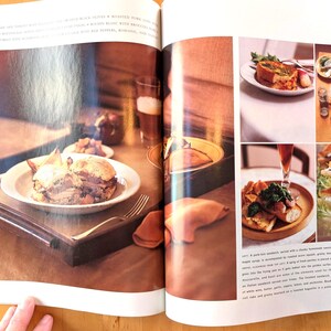 May include: A spread of food items, including sandwiches, on a wooden tray and plates. A sandwich on a white plate sits on a wooden tray. Other plates and glasses are also visible, with a fork and a napkin.