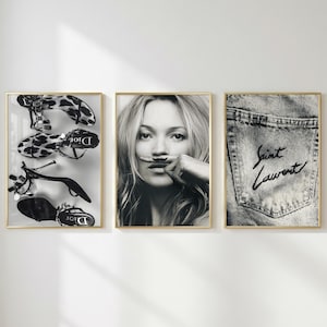 May include: Three framed wall art prints in gold frames. The left print shows black and white high-heeled sandals. The centre print is a black and white portrait of a person with a moustache drawn on their finger. The right print shows a denim pocket.