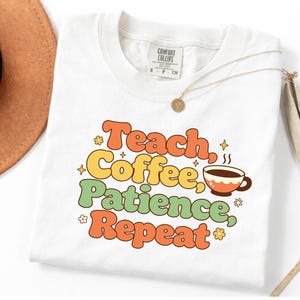 Puede incluir: Camiseta blanca con las palabras "Teach, Coffee, Patience, Repeat" en naranja, amarillo y verde. Se incluye un gráfico de taza de café. La camiseta tiene cuello redondo y mangas cortas. Una cadena de oro está drapeada sobre la camiseta.