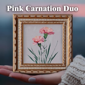 May include: A square oil painting titled Pink Carnation Duo featuring two pink carnations with green stems and leaves on a light gray background, encased in an ornate, textured gold frame with a decorative leaf-patterned border.