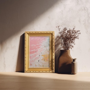 May include: A framed painting with a gold ornate frame depicts a beach scene with figures. The artwork features a pink and white sky, a sandy shore, and tiny figures. A brown vase with dried flowers and a small vase are next to the painting.