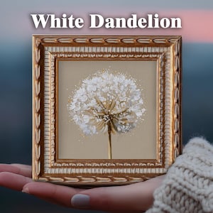 May include: A square framed painting titled White Dandelion featuring a textured white dandelion seed head against a solid beige background. The frame is ornate, metallic gold with a decorative carved pattern along the outer and inner edges.