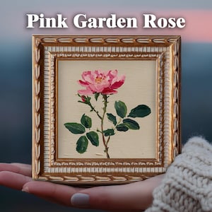 May include: A square painting of a pink garden rose with green leaves on a cream background, encased in an ornate gold frame. The text "Pink Garden Rose" is printed in white above the frame. The artwork features visible brushstrokes.