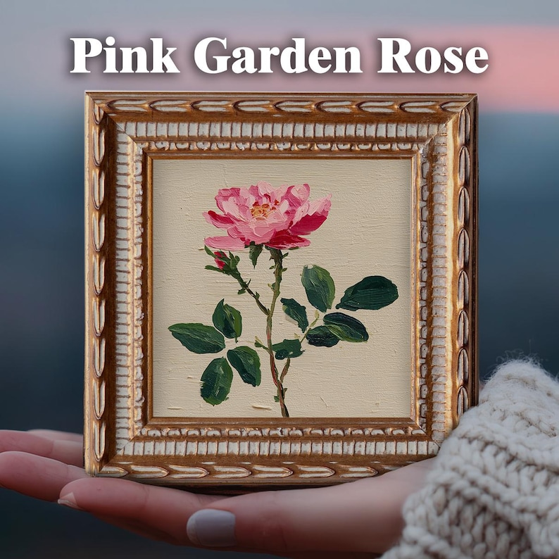 May include: A square painting of a pink garden rose with green leaves on a cream background, encased in an ornate gold frame. The text "Pink Garden Rose" is printed in white above the frame. The artwork features visible brushstrokes.