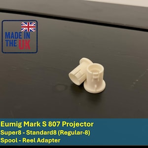 May include: Two off-white reel adapters for a Eumig Mark S 807 projector. The adapters are cylindrical with a flared base and a central opening. The image also includes a "Made in the UK" label.