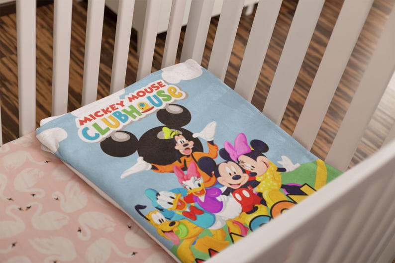 May include: A light blue blanket featuring the Mickey Mouse Clubhouse logo in red, yellow, and green text. The blanket displays a colorful graphic of Mickey Mouse, Minnie Mouse, Donald Duck, Daisy Duck, Goofy, and Pluto against a sky blue background.