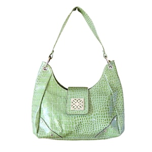 May include: A light green, faux-crocodile-skin shoulder bag with a single strap. The bag features a flap closure with a gold-colored, geometric design. The bag has a curved shape and a shiny finish.